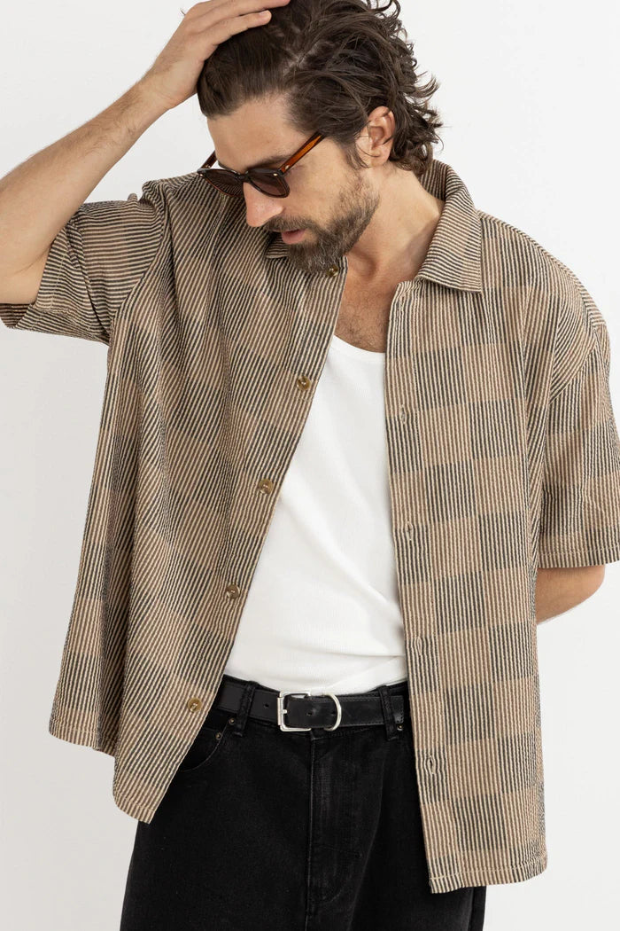Make a statement with the Tanner Check SS Shirt in Tobacco. This relaxed-fit shirt features a plastic button closure, a one-piece collar, and a straight hem, ensuring a polished look for casual outings. The Rhythm labels and trims complete this stylish piece, perfect for layering or wearing alone.