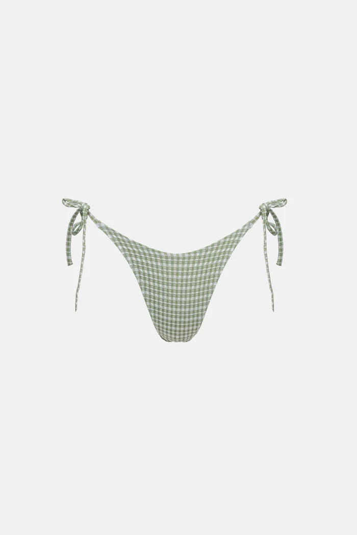 The Lola Check Tie Side Hi Cut Pant in Green features brief bottom coverage with adjustable tie sides for a personalized fit. Designed to sit high on the hips, it showcases scooped front waist shaping and zig-zag stitching at the waist and leg openings, finished with a metal coin logo for a stylish touch.