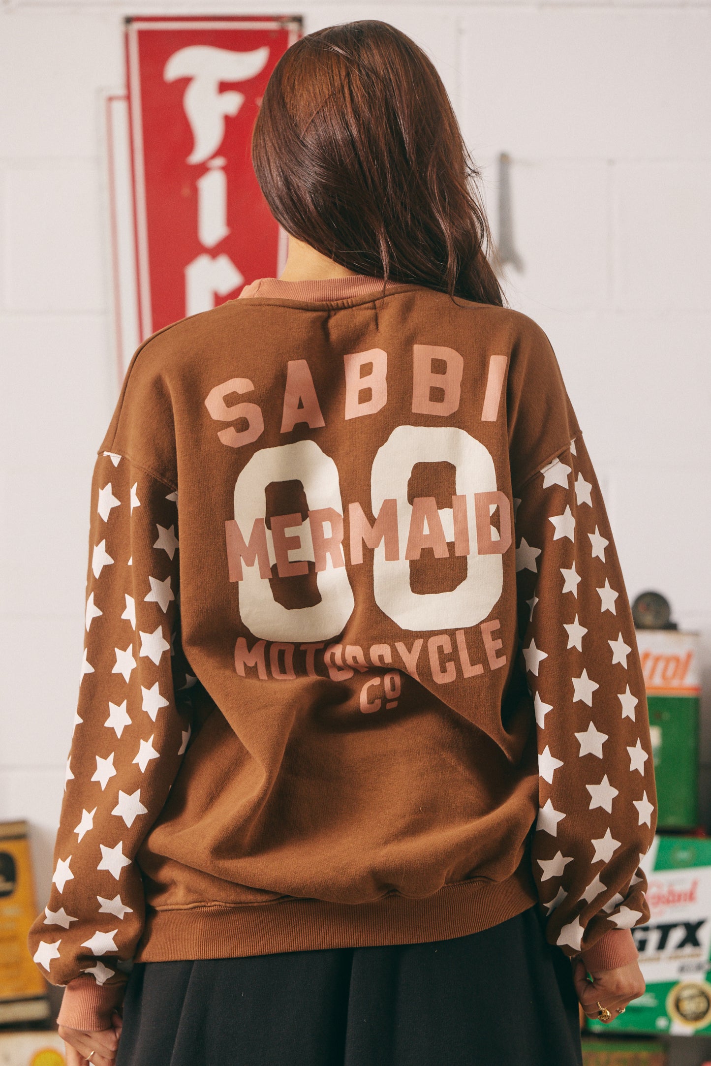 The Diego Jumper – Dream Big Brenda (Rich Clay)
Turn heads and stay toasty. The Diego Jumper in Rich Clay delivers serious vintage varsity vibes with a wild, wanderlust twist. Featuring SABBI’s signature “Dream Big Brenda” mermaid artwork front and centre, and oversized varsity-style back branding, this jumper is made for rule-breakers with heart.
The sleeves steal the spotlight with bold white star prints — a nod to rebel spirit — while the plush fleece interior keeps you cozy from coast to campfire.