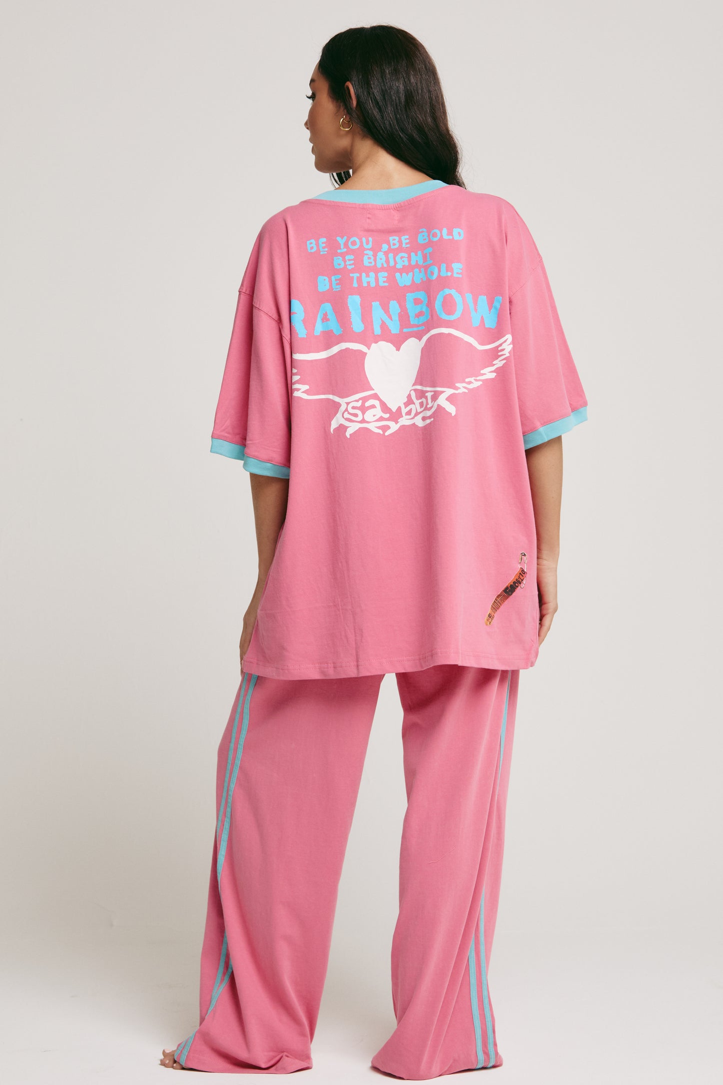 Turn up the colour and channel your inner festival queen in The Carnivale Tee - Pink — a bold explosion of fun, freedom, and retro energy.
Crafted from soft, breathable cotton, this oversized statement tee is all about comfort with major attitude. The vibrant pink base is perfectly contrasted with aqua trims, giving it that pop of playfulness Sabbi is known for. Front and centre is the iconic Carnivale graphic — a celebration of creativity, chaos, and confidence — while the back features Sabbi’s signature