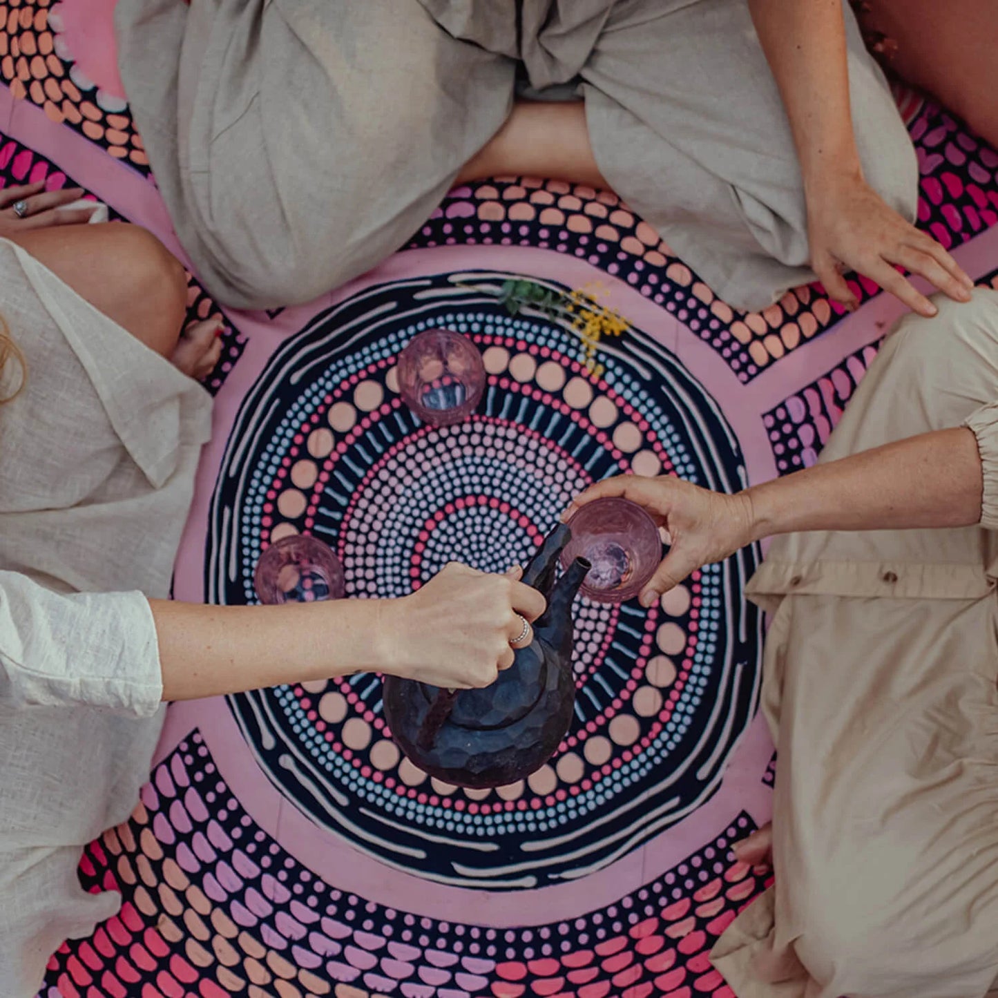 The first of our Artists Series, the Miinggi Jaanymili Picnic Rug features Indigenous artists duo Miimi and Jiinda’s artwork. The symbol in the middle represents a meeting place where people come together and connect. The circles around the outside are neighbouring tribes, friends and family that journey along the pathways, meeting in the middle to share stories, culture, food and celebrations.