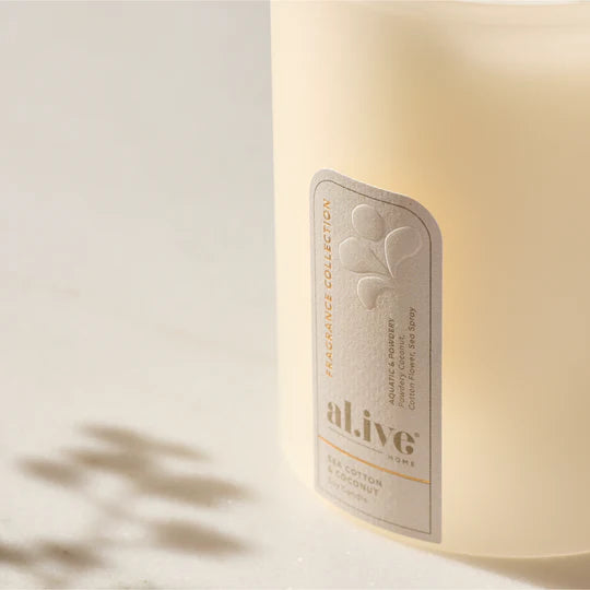 al.ive body - A calming Soy Candle blending powdery cotton flower with ocean air and delicate florals. Soft coconut and sandalwood create a serene atmosphere that evokes clean linens drying in a sea breeze.