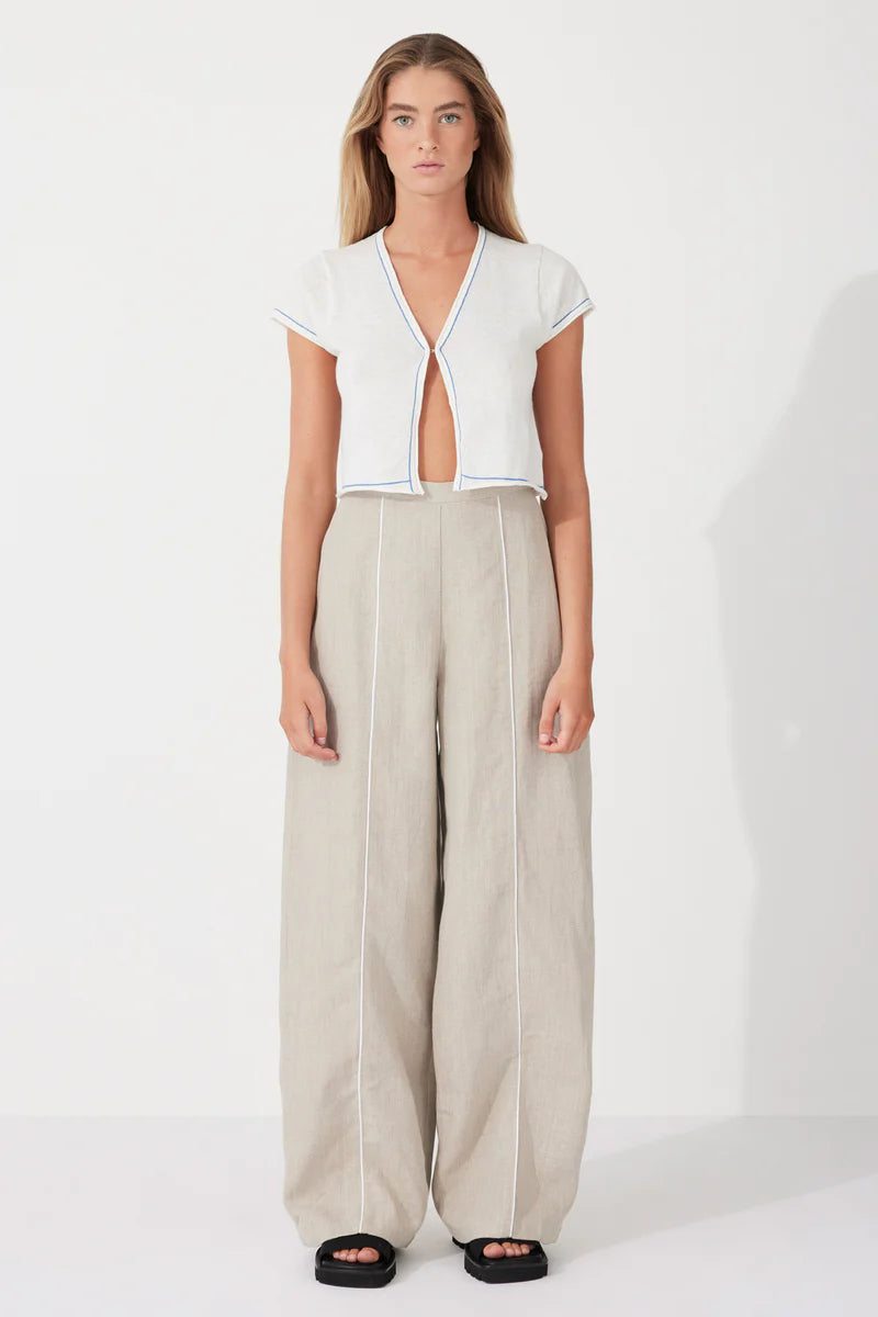 The Husk Contrast Linen Pant by Zulu & Zephyr is effortlessly wearable, to be dressed up or down, featuring a high fixed waistband with back zip closure, a loose tailored leg, and contrast piping detailing.