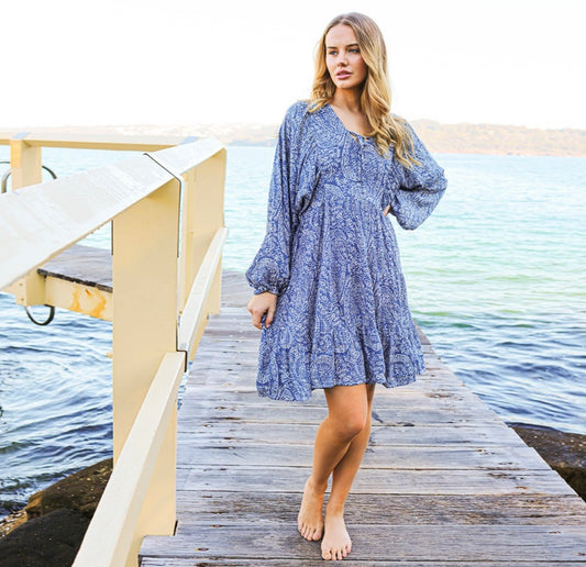 The Catherine Dress in blue and white by Primrose the Label is the perfect relaxed fit beach to bar dress. Featuring puff long sleeve with elastic cuff, V-neckline with tie detail, button front detail on bodice, adjustable tie-string at back, tiered flounce skirt and on-seam hip pockets.