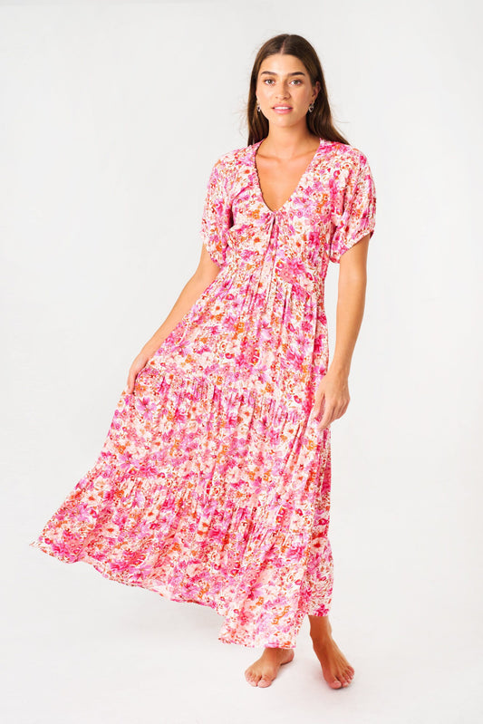 Flowy lightweight rayon. V-neck with adjustable tie-string. Short puff sleeves. Shirred elastic waistband at back. On-seam hip pockets. Tiered Flounce Midi length design