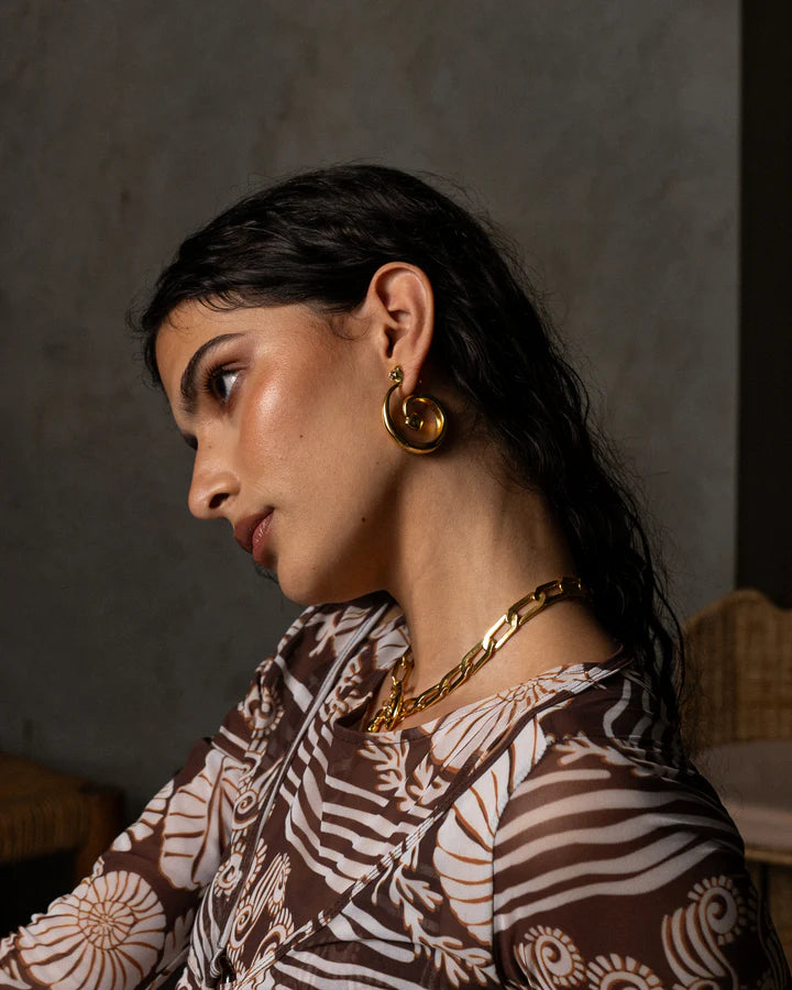 These beauties boast ethereal beauty and earthy grounding, the GAIA Earrings in Gold will have you feeling like a sophisticated goddess. Inspired by the beauty of natural stone and the fluidity of water, these chic hoop style earrings feature an elegant spiral motif that adds a chic touch to any look, and displaying faceted sparkling White CZ stones. A must-have for those who are looking to effortlessly standout.