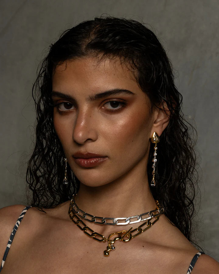 The EVERLEIGH Necklace in Gold commands attention... She exudes strength, sophistication with a hint of 'effortless cool girl' what more could we ask for!? Boasting a beautifully unique t-clasp designed around a fluid motif, adorned with droplets of mix metals, nestled between a chunky angular link chain, evoking the balance between hard and soft. Effortlessly layered or a standout all on her own. The Everleigh Necklace is that unique piece you've been searching for!
