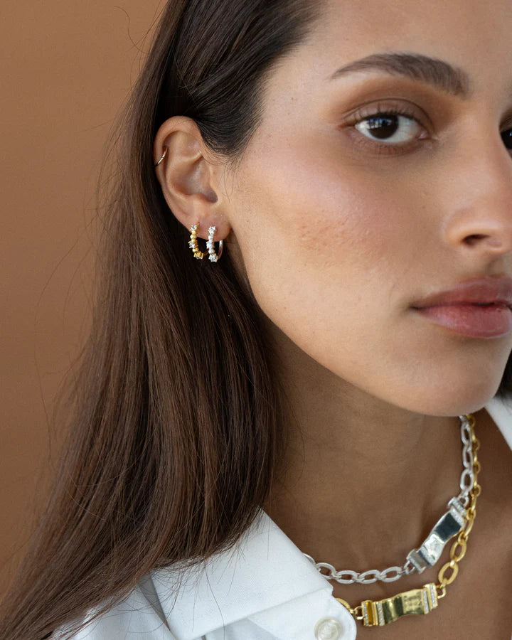 Gia is a fashionable huggie hoop that adds a touch of sparkle to your jewellery collection. It's the perfect size for a second piercing or layering with bigger hoops, featuring inset CZ stones and a high polish finish. Gia is an ideal choice for those who need an accessory that packs a punch, and proves that a tiny size can still make a big statement.