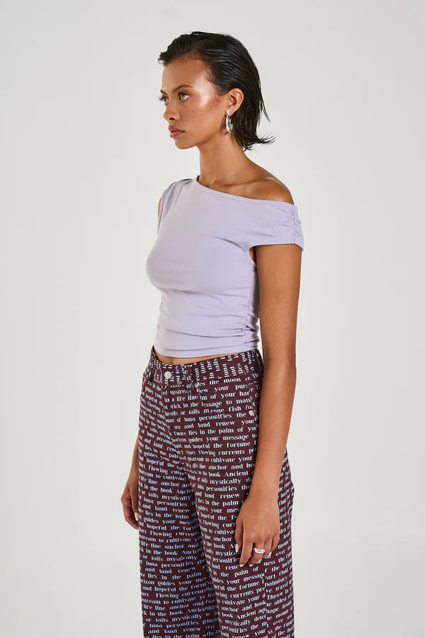 The Off Shoulder Tank in a seafoam lilac hue has been constructed from a stretchy cotton blend, featuring a ruched midsection for a flattering fit.