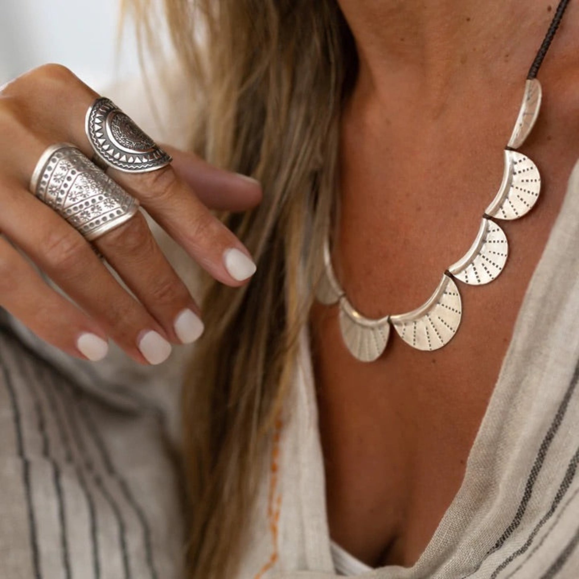 The Pippies Necklace by Embella features nine hand-pressed Hilltribe silver pendants strung onto an adjustable polywax cord.