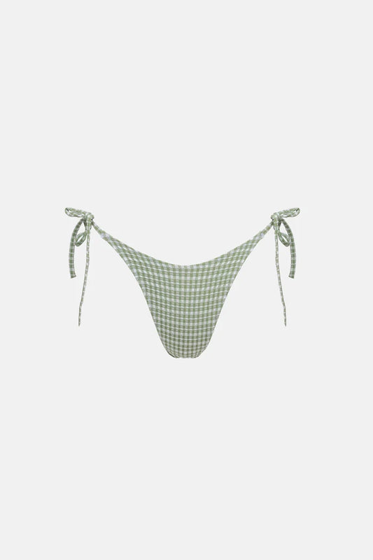 The Lola Check Tie Side Hi Cut Pant in Green features brief bottom coverage with adjustable tie sides for a personalized fit. Designed to sit high on the hips, it showcases scooped front waist shaping and zig-zag stitching at the waist and leg openings, finished with a metal coin logo for a stylish touch.