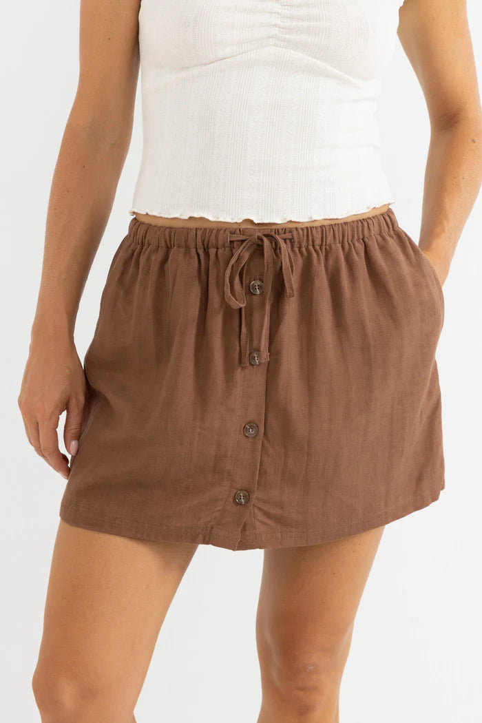Rhythm Livin - This mid-high rise skort in Chocolate seamlessly blends comfort and style. Featuring an elasticated waistband and self drawcord, it provides a relaxed fit with internal shorts for added coverage. The front button opening adds a chic touch, while the 3.5 cm inseam ensures ease of movement for all-day wear.