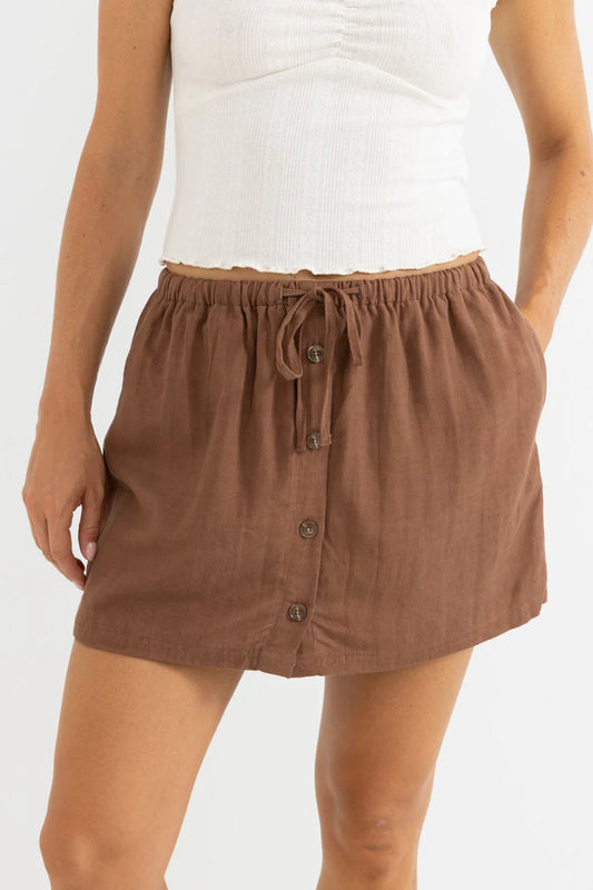 Rhythm Livin - This mid-high rise skort in Chocolate seamlessly blends comfort and style. Featuring an elasticated waistband and self drawcord, it provides a relaxed fit with internal shorts for added coverage. The front button opening adds a chic touch, while the 3.5 cm inseam ensures ease of movement for all-day wear.