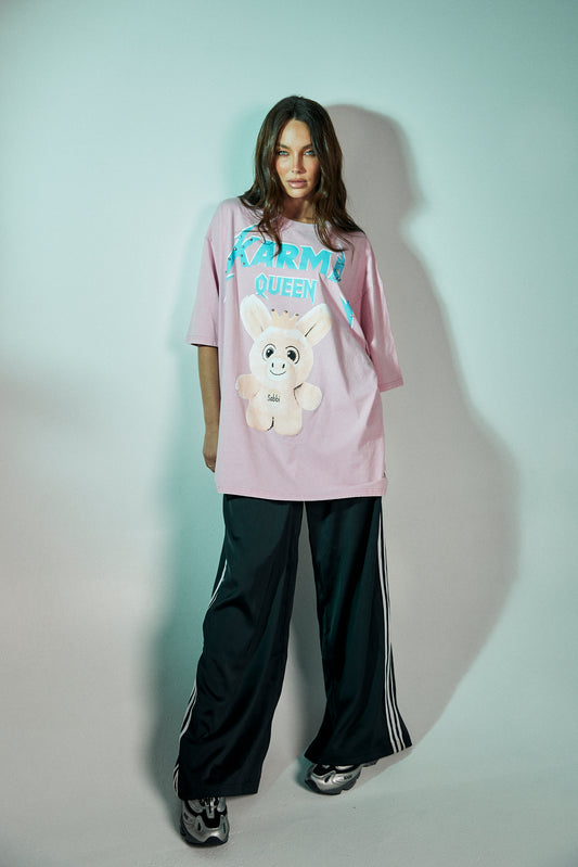 Step into your power with the Karma Queen Bling Tee in Pink – a bold mix of playful charm and streetwear edge. Crafted from 100% cotton with a relaxed, oversized fit, this tee features a statement graphic of the Karma Queen crowned character, brought to life with sparkling rhinestone embellishments for that extra dose of bling.
