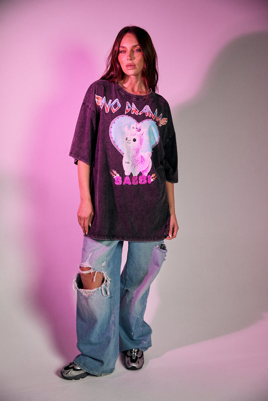 Keep it chill and playful with the No Drama Llama Bling Tee. Designed in a relaxed, oversized fit, this black vintage-wash tee is all about fun with its bold, sparkling graphic of a sassy llama framed by a dreamy heart. The rhinestone embellishments bring extra bling to your casual wardrobe, while the cheeky back print – “I Don’t Do Drama, I Snack” – seals the deal on your effortlessly cool vibe.
