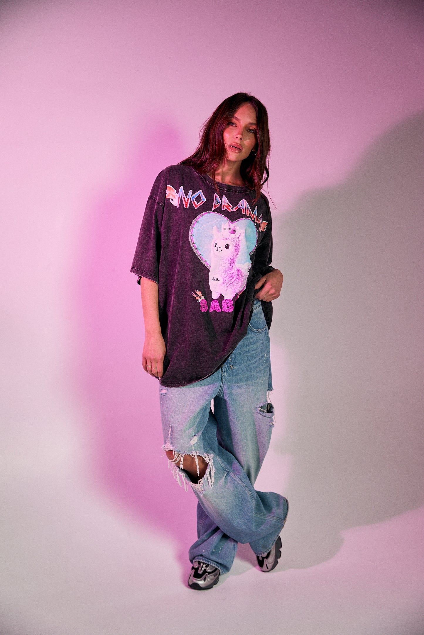 Keep it chill and playful with the No Drama Llama Bling Tee. Designed in a relaxed, oversized fit, this black vintage-wash tee is all about fun with its bold, sparkling graphic of a sassy llama framed by a dreamy heart. The rhinestone embellishments bring extra bling to your casual wardrobe, while the cheeky back print – “I Don’t Do Drama, I Snack” – seals the deal on your effortlessly cool vibe.
