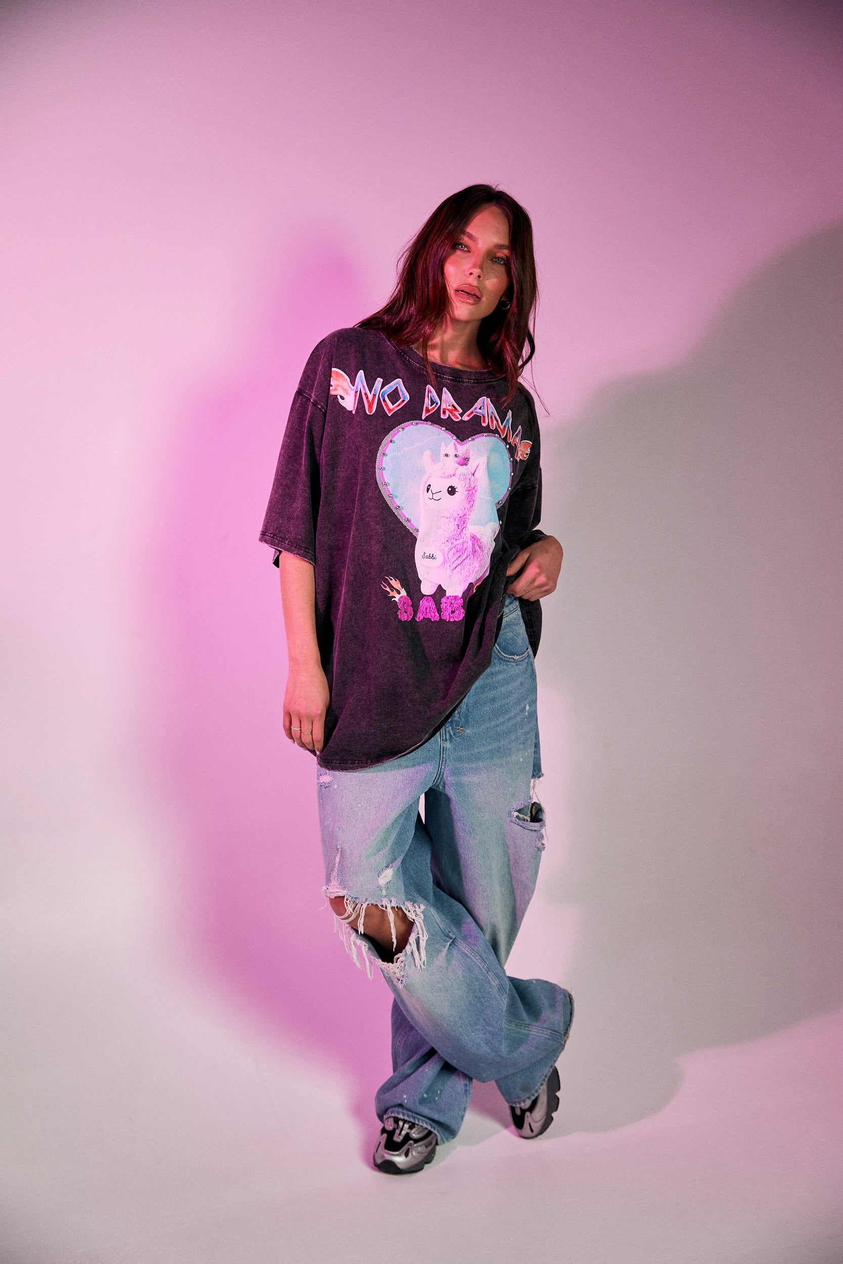 Keep it chill and playful with the No Drama Llama Bling Tee. Designed in a relaxed, oversized fit, this black vintage-wash tee is all about fun with its bold, sparkling graphic of a sassy llama framed by a dreamy heart. The rhinestone embellishments bring extra bling to your casual wardrobe, while the cheeky back print – “I Don’t Do Drama, I Snack” – seals the deal on your effortlessly cool vibe.
