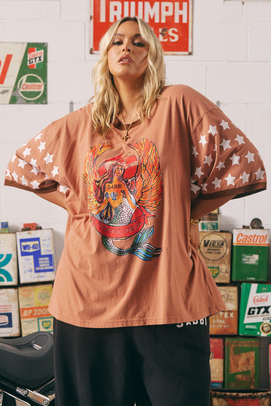 The Dream Big Brenda Clay Tee

Make a statement without saying a word. The Dream Big Brenda Tee is a fearless fusion of vintage Americana and rebellious femme energy. Featuring a bold winged mermaid graphic emblazoned across the chest and “MERMAID MOTORCYCLE CO” on the back, this oversized tee celebrates every wild-hearted wanderer who dreams big and rides free.