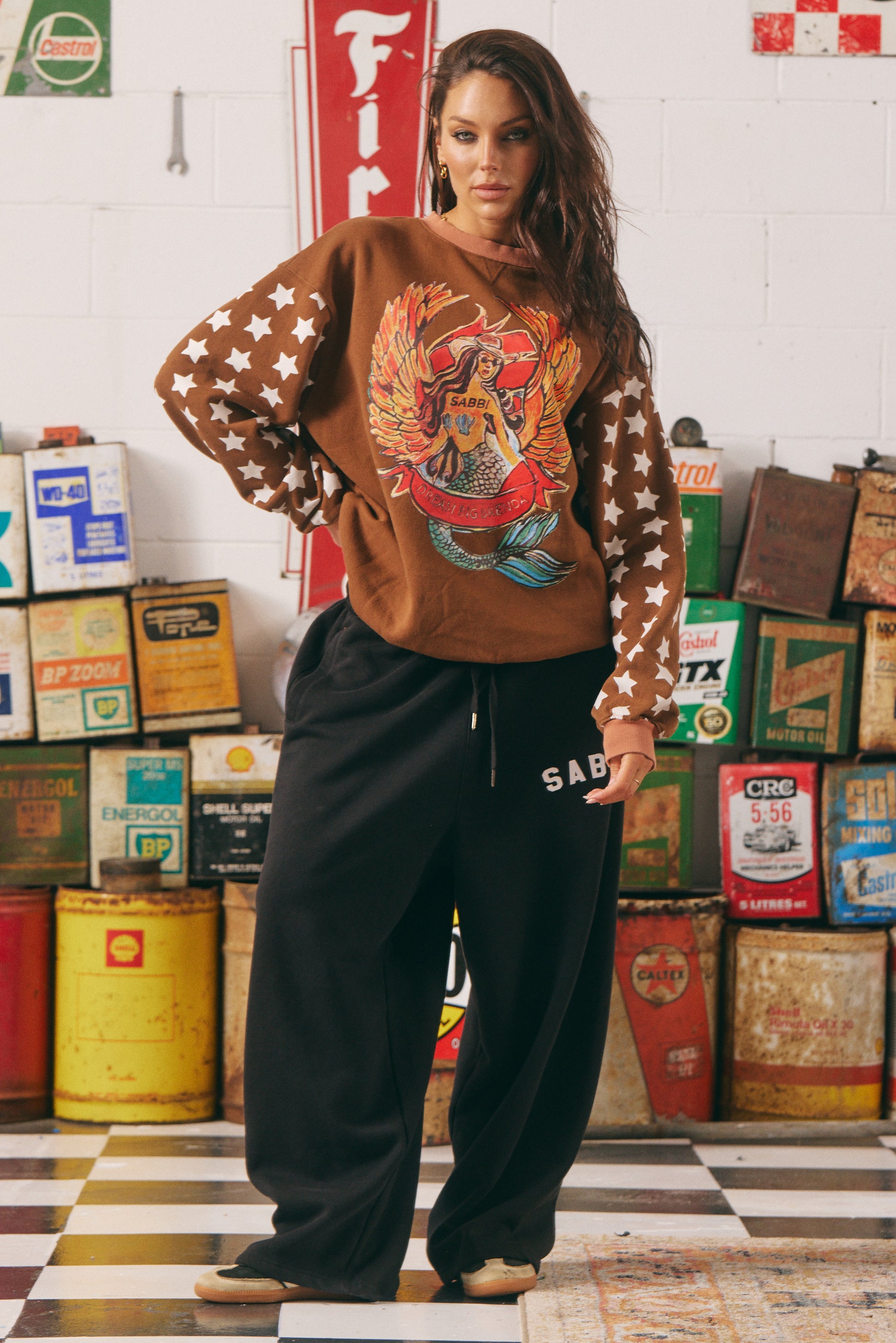 The Diego Jumper – Dream Big Brenda (Rich Clay)

Turn heads and stay toasty. The Diego Jumper in Rich Clay delivers serious vintage varsity vibes with a wild, wanderlust twist. Featuring SABBI’s signature “Dream Big Brenda” mermaid artwork front and centre, and oversized varsity-style back branding, this jumper is made for rule-breakers with heart.

The sleeves steal the spotlight with bold white star prints — a nod to rebel spirit — while the plush fleece interior keeps you cozy from coast to campfire.