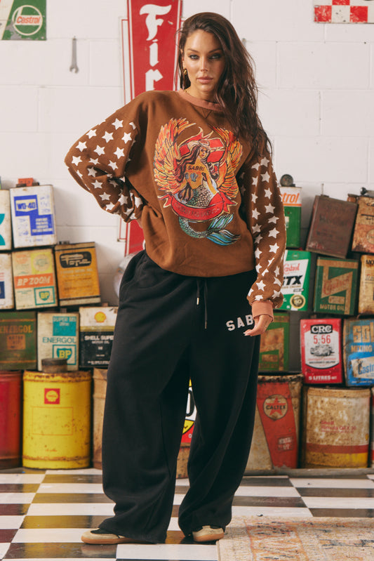 The Diego Jumper – Dream Big Brenda (Rich Clay)

Turn heads and stay toasty. The Diego Jumper in Rich Clay delivers serious vintage varsity vibes with a wild, wanderlust twist. Featuring SABBI’s signature “Dream Big Brenda” mermaid artwork front and centre, and oversized varsity-style back branding, this jumper is made for rule-breakers with heart.

The sleeves steal the spotlight with bold white star prints — a nod to rebel spirit — while the plush fleece interior keeps you cozy from coast to campfire.