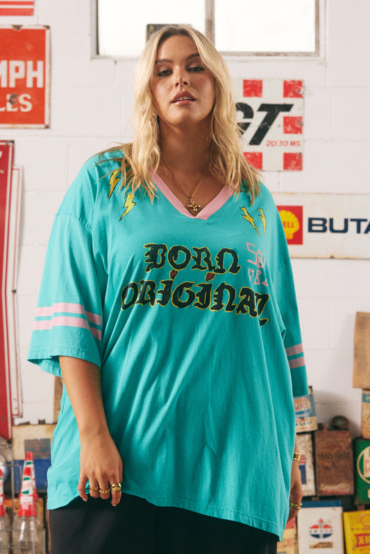 The Born Original Tee – Teal &amp; Pink
Fuel your fire and wear your power proudly in the Born Original Tee – Teal &amp; Pink. This oversized, vintage-sport inspired tee features statement gothic lettering, contrast pink varsity stripes, and bold yellow lightning bolts for an electrifying twist. The teal cotton base brings a fresh pop of colour, while the custom artwork on the back — winged boots and affirmations — reminds you that the world is better with your original energy. Equal parts comfy and cool, t