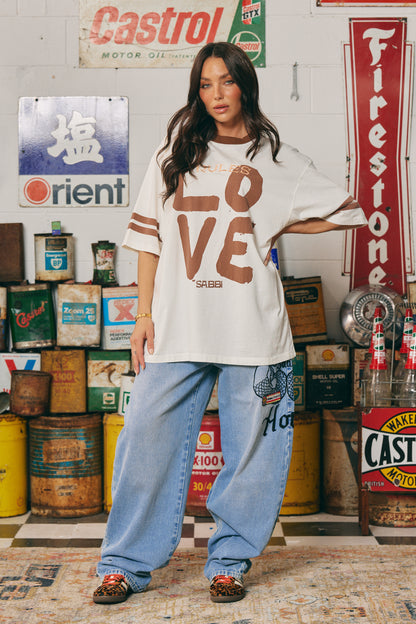 The Love Revolution Tee – Off White
Make a statement in soft neutrals with the Love Revolution Tee – Off White. Featuring bold chocolate-toned "LOVE" lettering, subtle pink rules detail, and varsity-inspired sleeve stripes, this oversized tee blends comfort with confident energy. Crafted from soft cotton with a relaxed fit, it's perfect for laid-back days or styled up with standout denim. Whether you're breaking the rules or rewriting them — this tee is all about leading with love.

