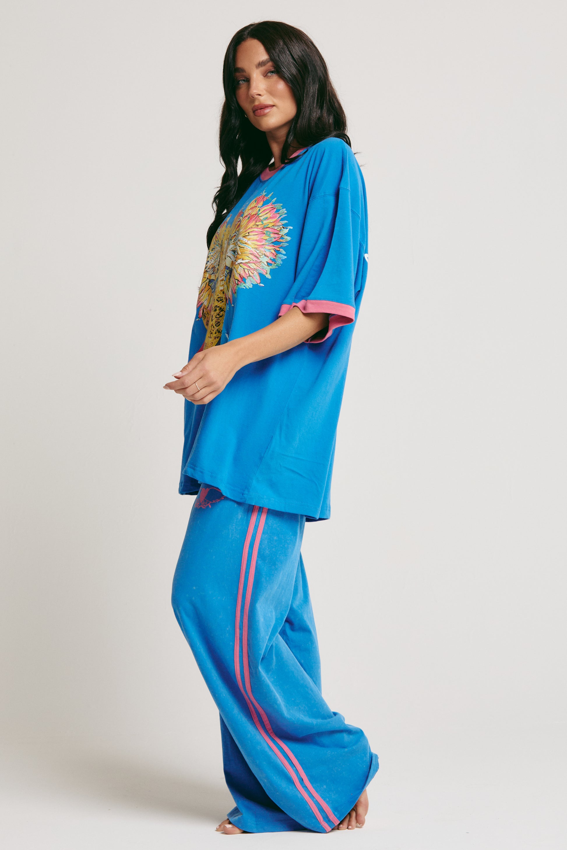 Step right up — it’s showtime with The Carnivale Tee - Blue, a bold celebration of colour, creativity, and unapologetic self-expression.

Crafted from soft, breathable cotton, this oversized tee features a striking electric blue base with fluro pink contrast trims for that vibrant Sabbi punch. The front showcases an iconic Carnivale-inspired graphic, while the back spreads good vibes with the uplifting message: “Be You. Be Bold. Be Bright. Be the Whole Rainbow.”