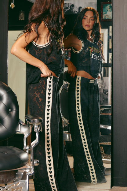 Make a statement in The Raving Hearts Lace Pants - Black, where grunge meets goddess. Crafted from soft, floral lace with a sheer finish, these pants embody the perfect clash of romance and rock ‘n’ roll. The relaxed, wide-leg silhouette flows effortlessly while the contrast heart trim running down each leg adds a bold, playful twist.