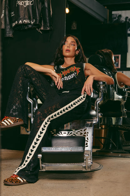 Make a statement in The Raving Hearts Lace Pants - Black, where grunge meets goddess. Crafted from soft, floral lace with a sheer finish, these pants embody the perfect clash of romance and rock ‘n’ roll. The relaxed, wide-leg silhouette flows effortlessly while the contrast heart trim running down each leg adds a bold, playful twist.