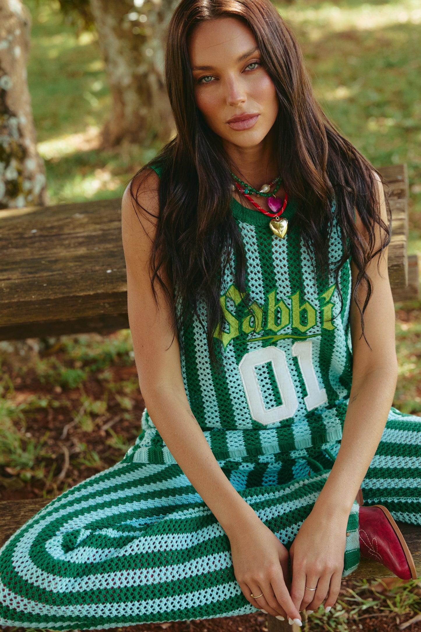 THE KNIT B-BALL SINGLET – GREEN STRIPE - GREEN

Meet the knit that brings big energy everywhere it goes. The Knit B-Ball Singlet in Green Stripe is a vibrant, retro-sport moment crafted for the bold, the playful, and the ones who refuse to blend in. Hand-crocheted with wide alternating green tones, this breathable mesh singlet delivers effortless comfort with serious statement power.