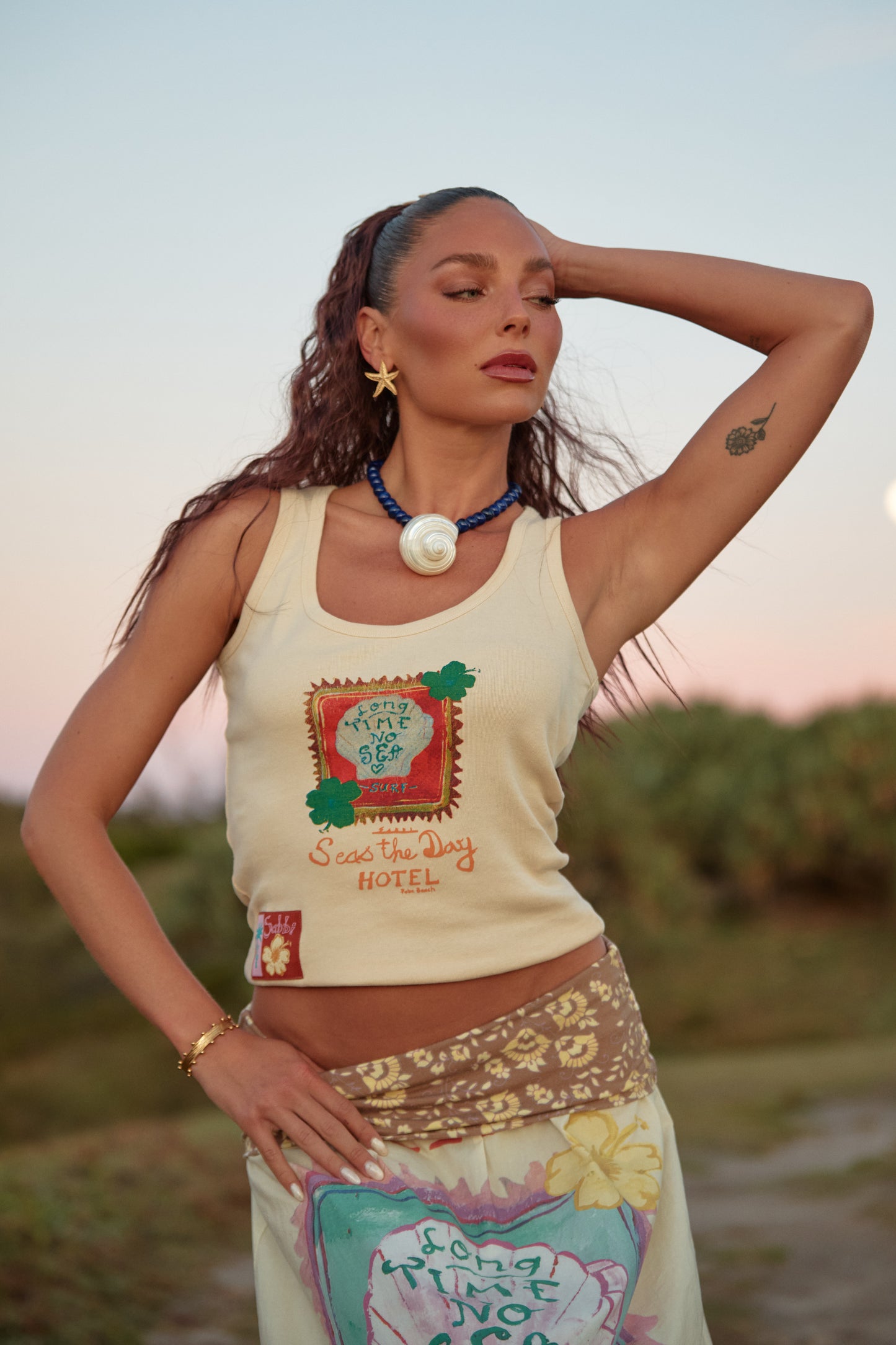 Sabbi - Sun-kissed, salty and made for endless summer days. The Long Time No Sea Tank is your go-to fitted tank for warm weather wanderings and coastal living. Designed with a flattering scoop neckline and a softly structured fit, this piece hugs just right while still feeling easy and breathable.