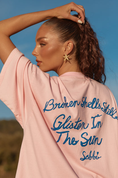 Sabbi -&nbsp;Playful, cheeky, and made to shine ✨
The Shell Titty Tee is your statement seaside tee—soft blush pink with shimmering shell detailing that catches the light like sun on water. Featuring our iconic shell motif on the front and a bold handwritten message on the back, this tee is all about confidence, coastal humour, and unapologetic fun.

