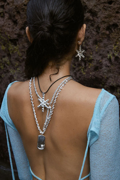 Understated and powerful, the Cypress Necklace in silver is a sculptural tribute to identity, elegance, and the enduring pull of the sea. Crafted with a thick, twisted rope-style chain, it features a modern pendant inspired by the shape of a traditional dog tag—reimagined with softened lines and a refined finish. At its center rests a luminous freshwater pearl, adding a touch of organic beauty.