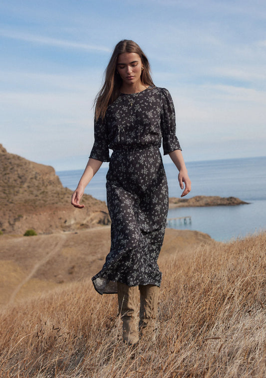 The Aruna midi dress in classic black Maeve print is one of our simple and elegant core pieces, featuring a round neckline, short sleeves with frill, an elasticated waistband, and a blouson top flowing into a flattering bias-cut skirt that falls into a draped hem. What's not to love?