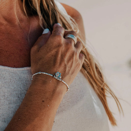 Introducing the Castaway Bracelet, a whimsical piece that embodies the spirit of carefree adventures and the enchantment of the ocean. Handcrafted with Hilltribe Silver, this bracelet features delightful details including a charming little fish charm, a radiant sun charm, and a playful bubble charm. Adorn your wrist with the Castaway Bracelet from Embella and let it transport you to a world of seaside bliss and wanderlust.