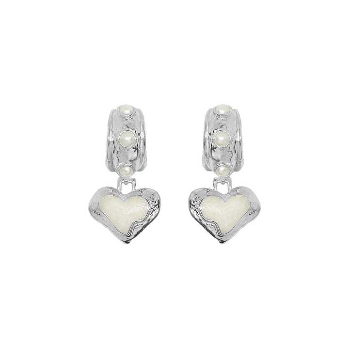 Timeless with a modern edge, the Elena Earrings in silver are a heart-shaped ode to the sunlit serenity of the Mediterranean. Crafted in radiant silver with hand-set freshwater pearls and pearlescent enamel detailing, they reflect the soft glow of sea and sky with every turn.