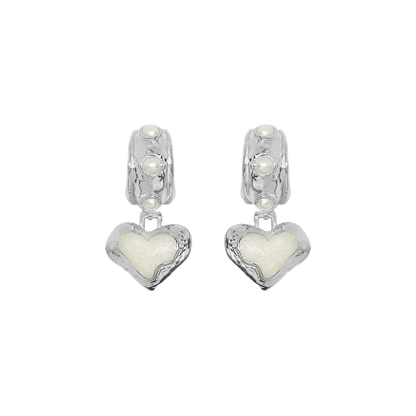 Timeless with a modern edge, the Elena Earrings in silver are a heart-shaped ode to the sunlit serenity of the Mediterranean. Crafted in radiant silver with hand-set freshwater pearls and pearlescent enamel detailing, they reflect the soft glow of sea and sky with every turn.