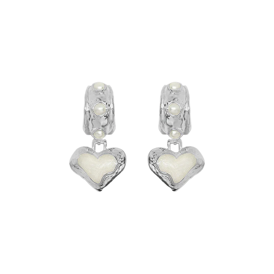 Timeless with a modern edge, the Elena Earrings in silver are a heart-shaped ode to the sunlit serenity of the Mediterranean. Crafted in radiant silver with hand-set freshwater pearls and pearlescent enamel detailing, they reflect the soft glow of sea and sky with every turn.