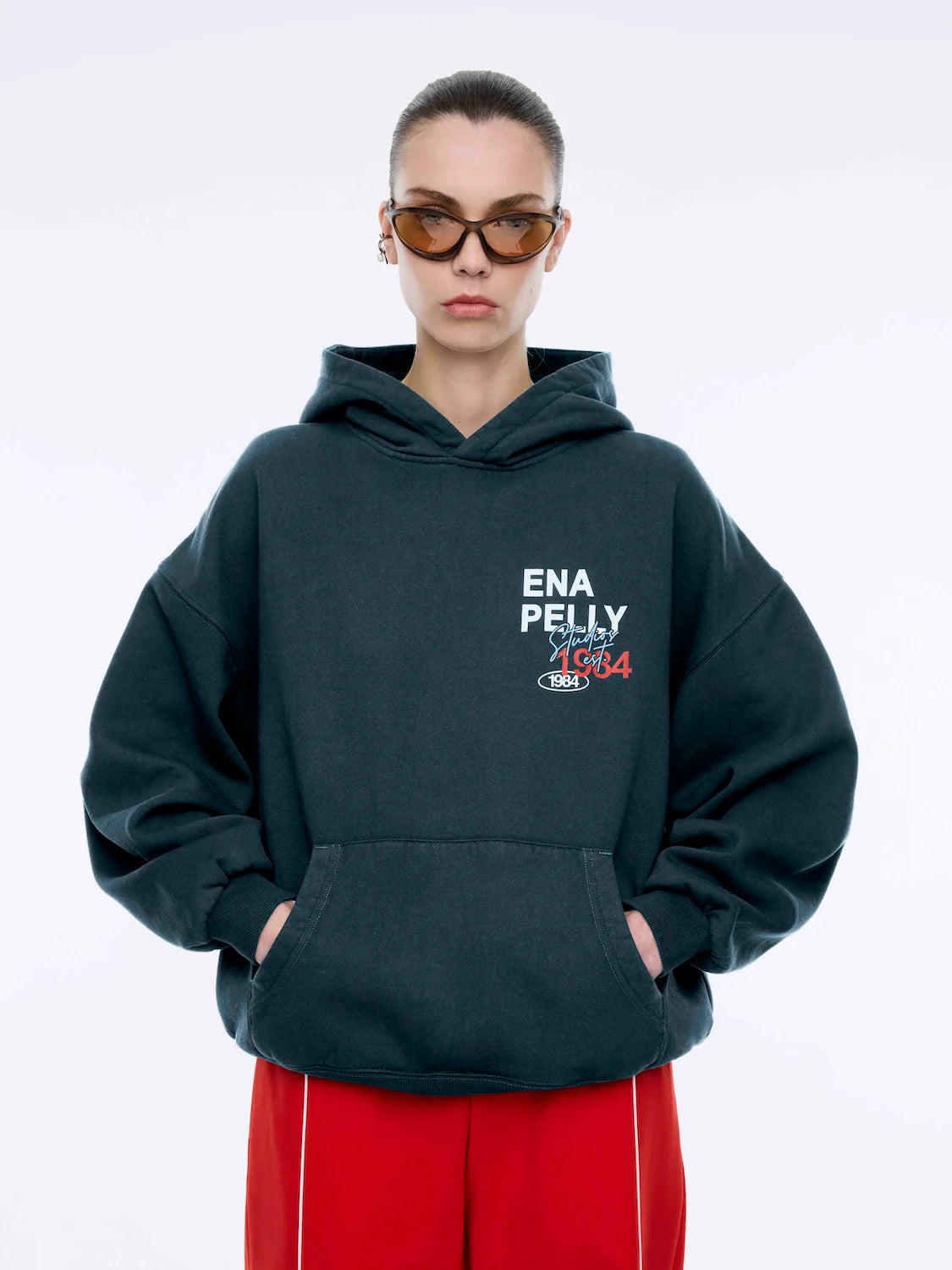 Where sporty meets streetwear cool — the Script Studio Hoodie is your go-to layer for off-duty confidence. Crafted from premium cotton terry in a vintage-washed black, this oversized hoodie features bold collegiate-inspired graphics on both the chest and back, including Ena Pelly’s signature “Studio 1984” motif.