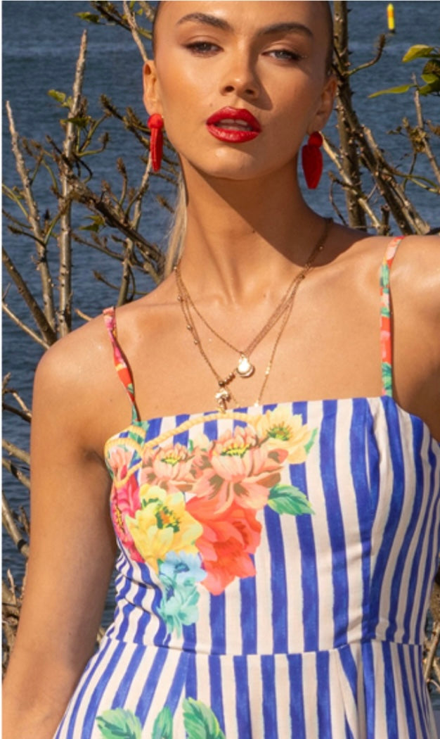 The Positano Sundress in Blue captures the spirit of summer in every stitch. With its picturesque coastal print, adjustable straps, and shirred back panel for a flattering fit, this dress blends comfort and sophistication effortlessly. The soft, lightweight linen-blend fabric flows beautifully, making it ideal for sunny days, weekend escapes, and long lunches by the sea. Finished with a chic exposed gold back zipper and cotton lining, it’s your go-to statement sundress of the season.