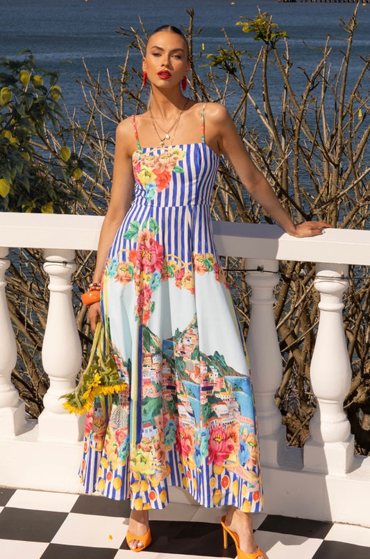 The Positano Sundress in Blue captures the spirit of summer in every stitch. With its picturesque coastal print, adjustable straps, and shirred back panel for a flattering fit, this dress blends comfort and sophistication effortlessly. The soft, lightweight linen-blend fabric flows beautifully, making it ideal for sunny days, weekend escapes, and long lunches by the sea. Finished with a chic exposed gold back zipper and cotton lining, it’s your go-to statement sundress of the season.