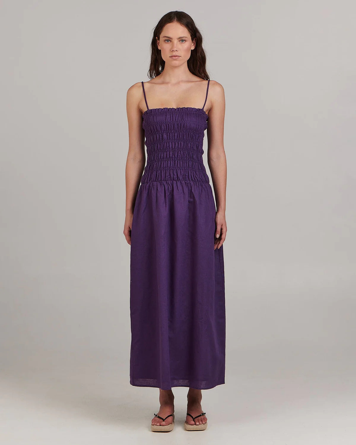 With a shirred bodice and flared skirt this elegant sundress makes a splash in a saturated purple hue. The shoestring straps can be worn as intended or tucked away to convert to a strapless dress. Wear with stacked heels for a night out or with bare feet by day