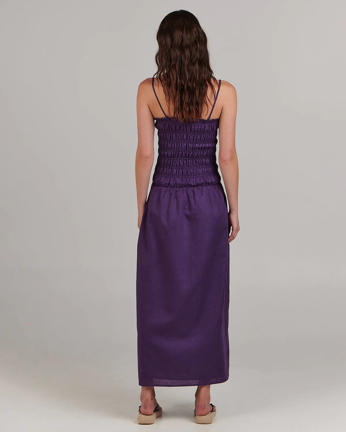 With a shirred bodice and flared skirt this elegant sundress makes a splash in a saturated purple hue. The shoestring straps can be worn as intended or tucked away to convert to a strapless dress. Wear with stacked heels for a night out or with bare feet by day