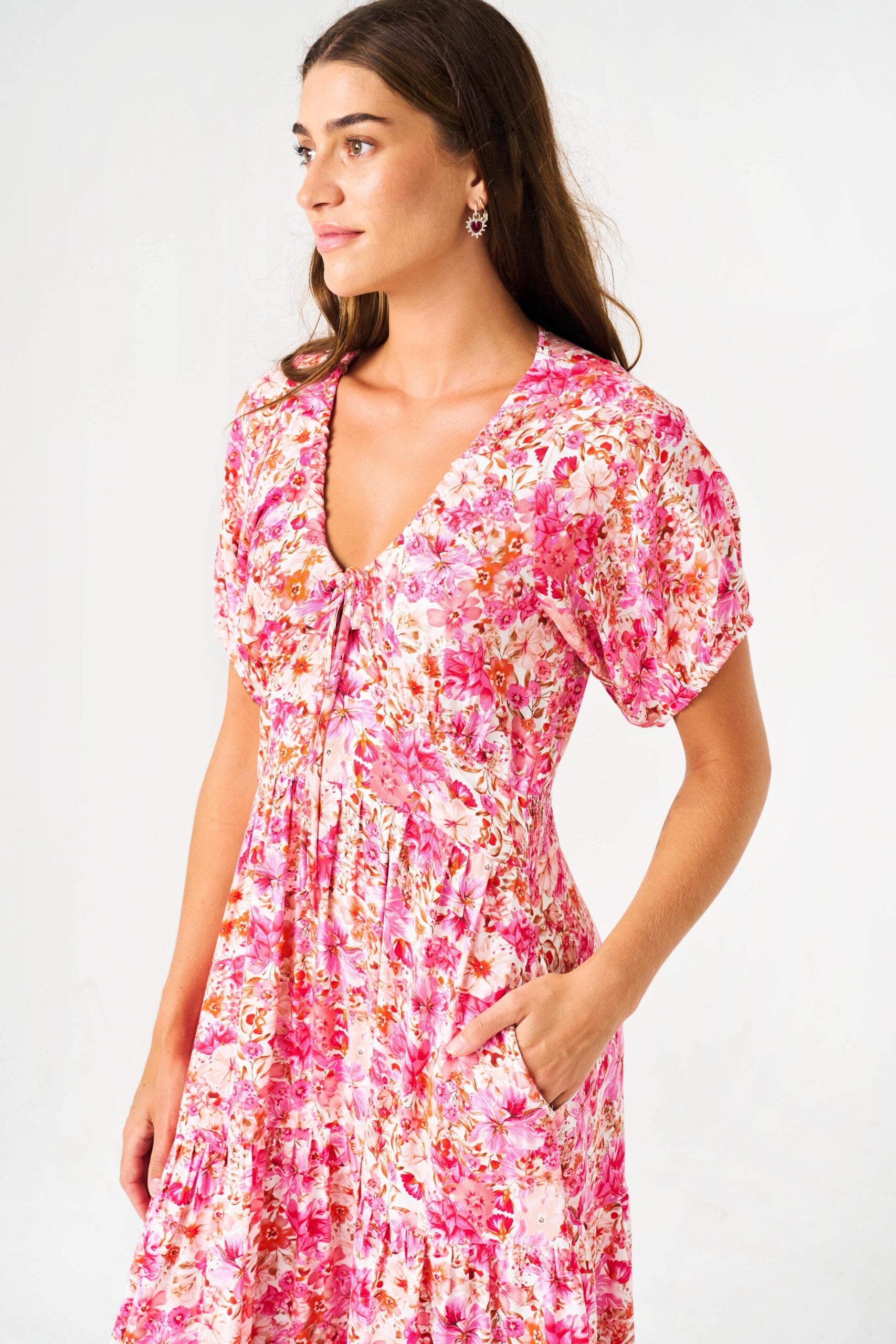 Flowy lightweight rayon. V-neck with adjustable tie-string. Short puff sleeves. Shirred elastic waistband at back. On-seam hip pockets. Tiered Flounce Midi length design