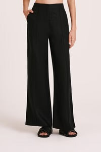 The Amani Tailored Linen pant in black is made from a premium linen which has been washed for a smooth, soft hand feel. The silhouette is a classic tailored fit with a high waist, wide legs and length finishing full length. Features include a functioning fly front, pin stitch on front leg and side seam pockets. 