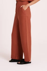 The Amani Tailored Linen pant in amber is made from a premium linen which has been washed for a smooth, soft hand feel. The silhouette is a classic tailored fit with a high waist, wide legs and length finishing full length. Features include a functioning fly front, pin stitch on front leg and side seam pockets. 