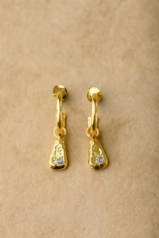 Get ready to dazzle with Ocea, the perfect huggie earrings for any occasion. The crushed gold design and sparkling blue sapphire stones will add a touch of elegance and playfulness to any outfit. Say hello to your new favorite accessory!

925 Gold Plated Sterling Silver&nbsp;
Sapphire Stones
Lead,Nickel &amp; Tarnish Free
Hypoallergenic
Waterproof