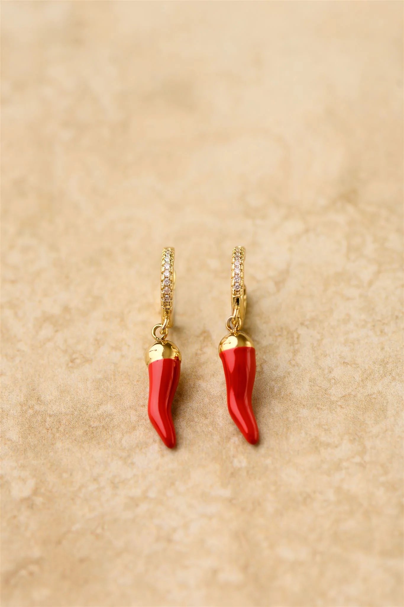 Spice up your jewelry game with our Cornicello Earrings! These unique earrings feature a chilli charm on a sparkling cubic zirconia hoop. Bring some good luck and a playful touch to any outfit.

925 Gold Plated Sterling Silver&nbsp;
Cubic Zircon
Lead,Nickel &amp; Tarnish Free
Hypoallergenic
Waterproof