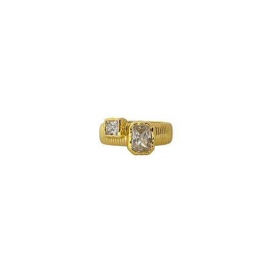 Elegant with a hint of edge, the Maia Ring is a modern relic inspired by radiant ancient craftsmanship. Featuring a ribbed, circular band in gold, it holds two rectangular cubic zirconia stones in textured bezel settings—designed to catch the light like sunlit waves.