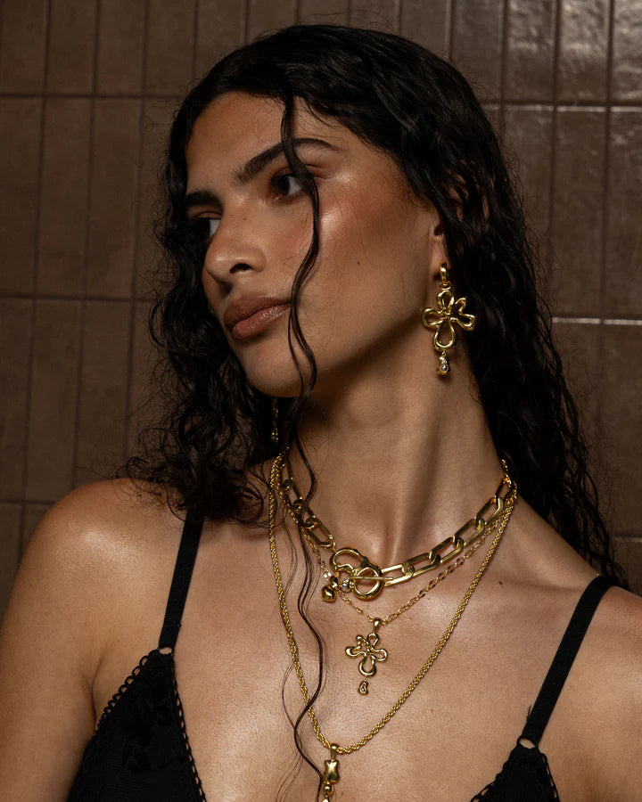 The DAHLIA Earrings in Gold evoke the playful side of nature’s elements, the ebbs and flows in water, the beautiful veining in untouched stone, the scalloping shores of the sea sides. The Dahlia boast a chic fluid motif suspended from a perfect and easy to wear mini hoop in a high polish finish. Sized to perfection suitable from day to night, these beauties are sure to become the favourites of the Ambrosia collection. Pair with the Maeve necklace to create a gorgeous matching set.